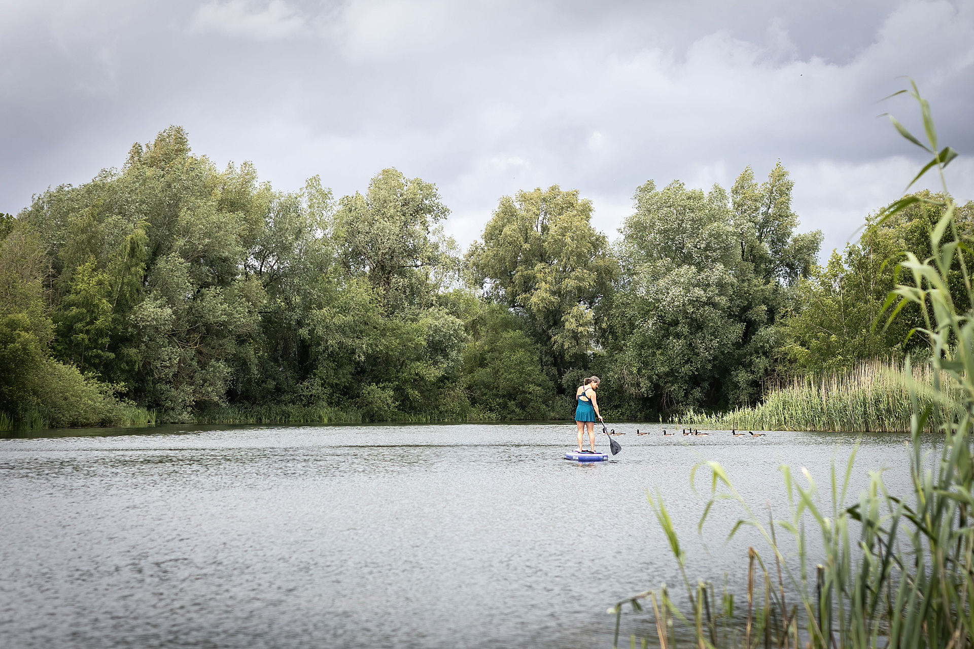 Suzanne on a stand-up paddleboard on a quiet lake surrounded by trees